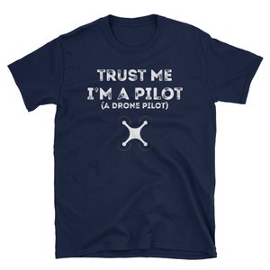 May include: A navy blue t-shirt with the text "TRUST ME I'M A PILOT (A DRONE PILOT)" in white. A white drone icon is below the text.