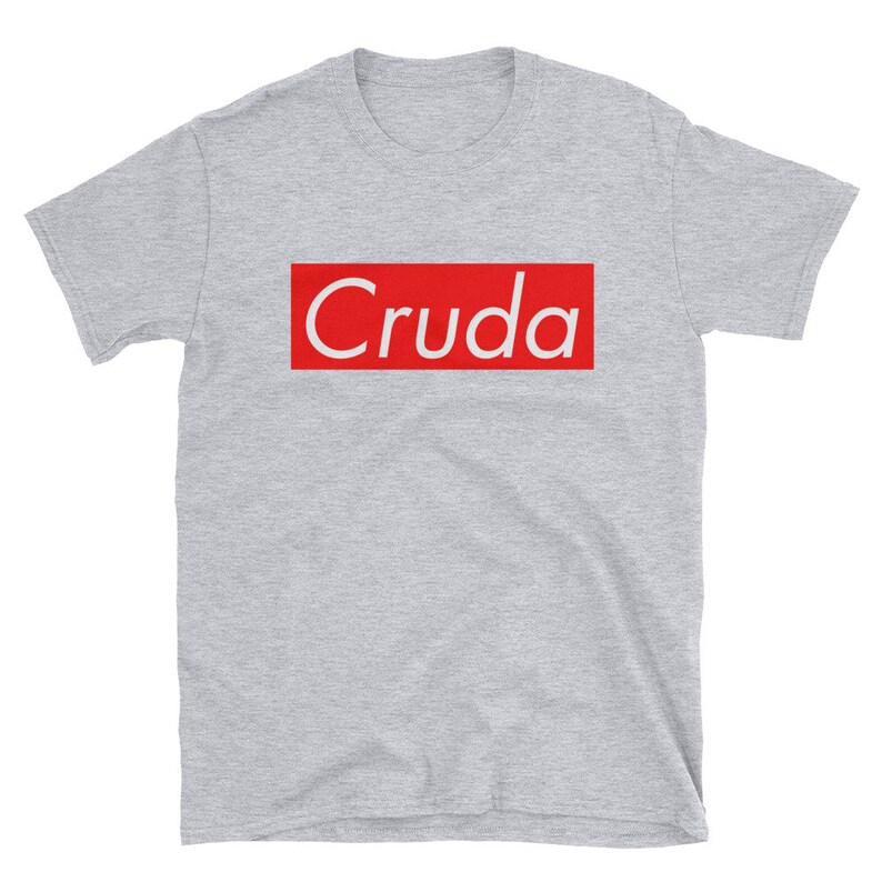 May include: A gray short-sleeved t-shirt with a red box that says "Cruda" in white text.