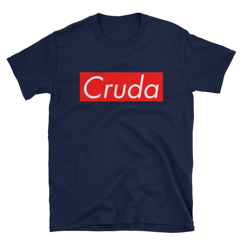 May include: A navy blue t-shirt with a red box and the word "Cruda" in white letters.