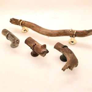 Peut inclure: Ensemble de poignées et boutons de meubles en bois flotté. Les poignées sont en bois naturel avec des accents métalliques dorés. Les boutons ont un design similaire, avec des formes et tailles variées. Quincaillerie pour meubles et décoration intérieure.