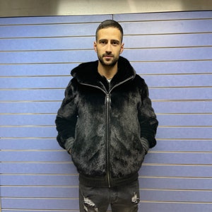 May include: A black fur bomber jacket with a zipper closure. The jacket has a stand-up collar and a ribbed knit trim at the cuffs and hem.