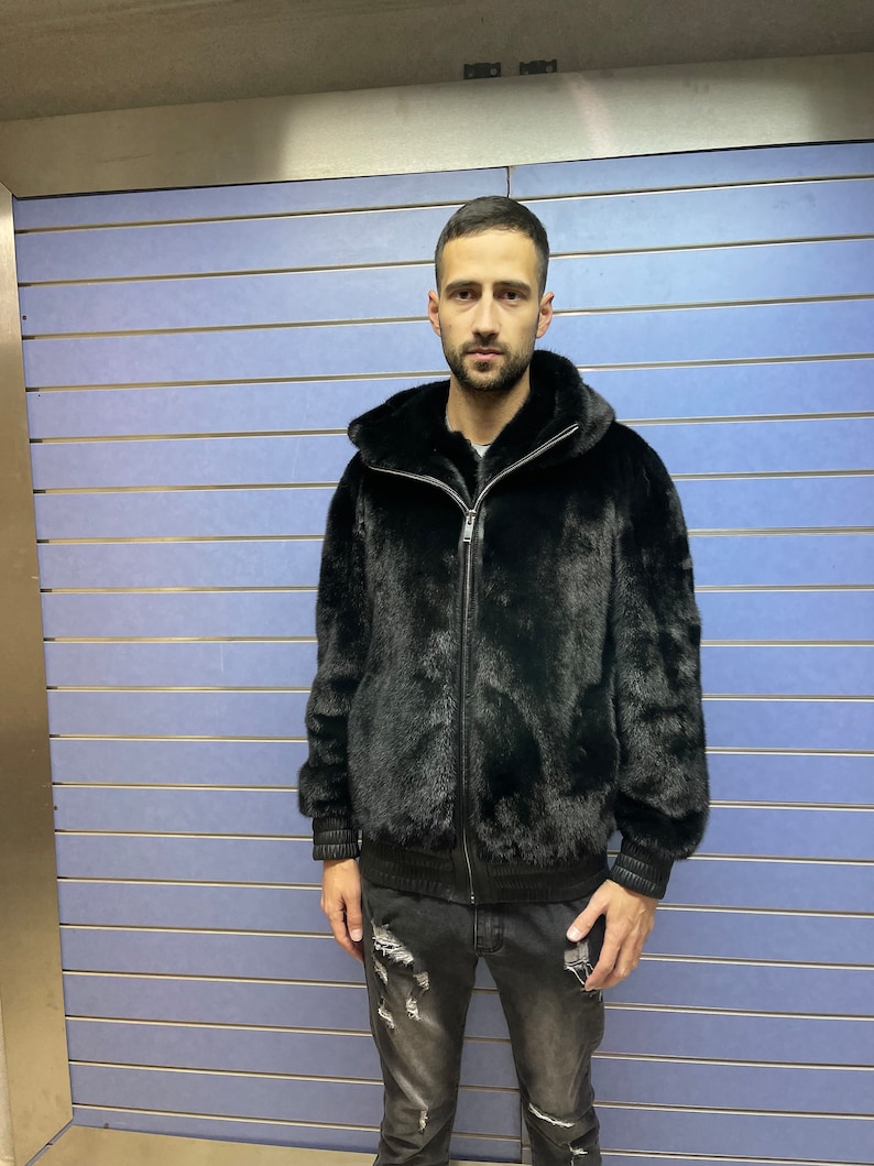 May include: A black fur bomber jacket with a zipper closure. The jacket has a hood and ribbed cuffs and waistband.