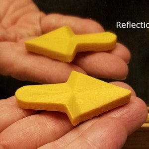 May include: Two yellow plastic arrow shapes, one pointing left and the other pointing right, are held in a person's hand. The arrow shapes are slightly curved and have a textured surface.
