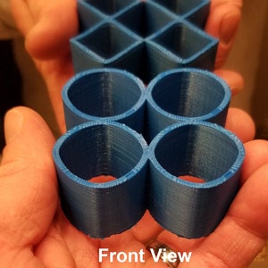 May include: Two 3D printed objects, one a blue geometric shape with a grid pattern and the other a blue shape resembling a figure eight, with the text "Mirror Image" and "Front View Quad Squirkle" below.