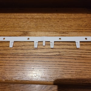 May include: White plastic curtain rod holder with five hooks.
