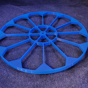 May include: A blue plastic circular mold with 16 sections, resembling a wheel with spokes. The mold is designed for creating decorative items or crafts.
