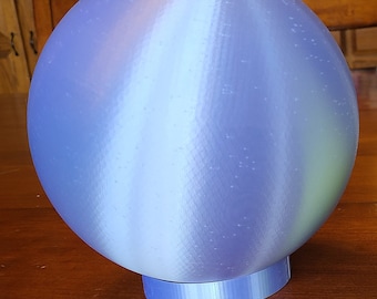 May include: A light blue sphere with a white and light blue striped pattern. The sphere is sitting on a light blue base.