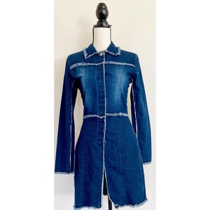 May include: A long-sleeved denim jacket with frayed edges and a button-up front. The jacket is a dark blue color and has a fitted silhouette.