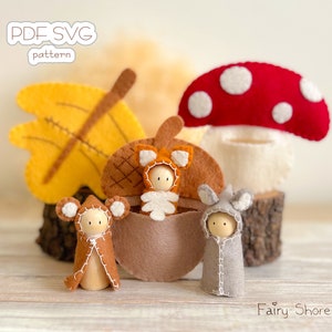 May include: Three wooden peg dolls wearing felt animal costumes, including a mouse, a fox, and a rabbit, displayed with felt accessories like a yellow leaf, a brown acorn, and a red mushroom. Text reads PDF SVG pattern and Fairy Shore.