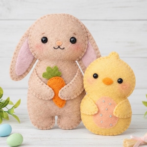 May include: Two felt Easter decorations: a tan bunny holding an orange carrot and a yellow chick with a pink egg design. Both have black eyes and are stitched with coordinating thread. The bunny has pink inner ears.