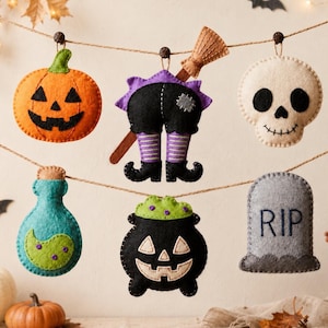 Peut inclure: Un ensemble de six décorations d'Halloween en feutrine suspendues à une ficelle, comprenant une citrouille orange, des jambes de sorcière avec un balai, un crâne blanc, une fiole turquoise, un chaudron noir et une pierre tombale grise avec RIP.