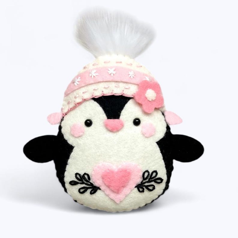 Valentine's Penguin felt ornament with pink hat, heart detail, and embroidery. DIY felt sewing pattern and SVG for Valentine's Day decor, love gifts, or easy craft projects. Perfect for beginners and experienced crafters to create a handmade decor