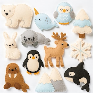 Puede incluir: Una colección de adornos de fieltro con temática de animales y naturaleza. Incluye un oso polar, un narval, un búho, un árbol de Navidad, un conejo, una foca, un ciervo, un copo de nieve, un pingüino, una morsa, montañas y una orca.