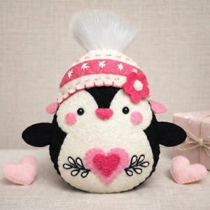 Valentine's Penguin felt ornament with pink hat, heart detail, and embroidery. DIY felt sewing pattern and SVG for Valentine's Day decor, love gifts, or easy craft projects. Perfect for beginners and experienced crafters to create a handmade decor