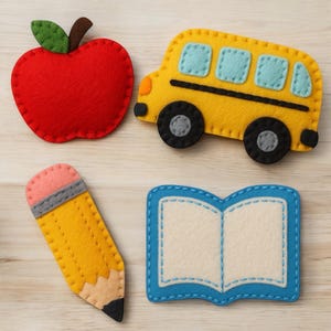 May include: A collection of felt school-themed items, including a red apple, yellow school bus, yellow pencil, and an open book with blue trim. The items are arranged on a light wood-grain surface.