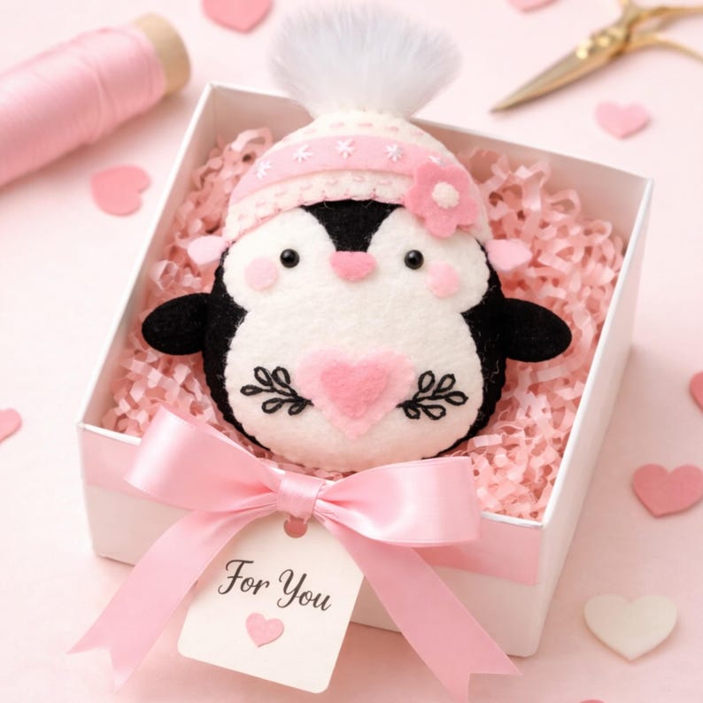 Valentine's Penguin felt ornament with pink hat, heart detail, and embroidery. DIY felt sewing pattern and SVG for Valentine's Day decor, love gifts, or easy craft projects. Perfect for beginners and experienced crafters to create a handmade decor