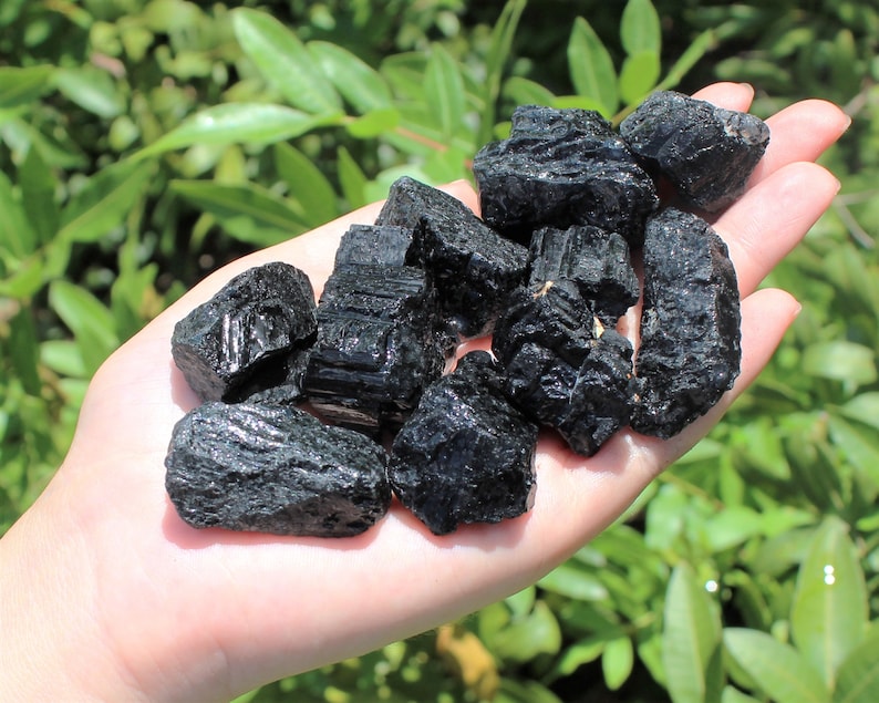 May include: A collection of black tourmaline crystals, also known as schorl, in various sizes and shapes. The crystals are raw and unpolished, with a natural, rough texture.