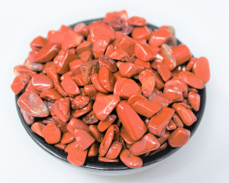 Puede incluir: Un cuenco lleno de piedras de jaspe rojo pulidas. Las piedras son lisas y pulidas, de un color rojo intenso.