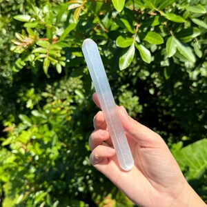 May include: A white selenite wand with a smooth, polished surface. The wand is about 10 inches long and has a slightly rounded end.