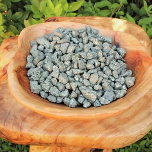 May include: A wooden bowl filled with a large amount of silver-colored pyrite crystals.