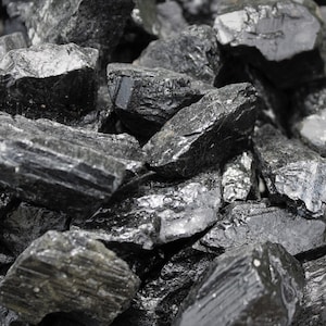 May include: A close-up of a pile of black tourmaline crystals. The crystals are rough and have a natural, unpolished look.