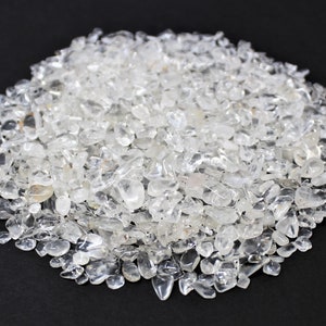 May include: A large pile of clear quartz crystals, also known as rock crystals. The crystals are small and irregularly shaped, with a translucent appearance.