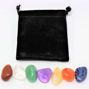 May include: Set of seven chakra stones in a black velvet pouch. The stones are red, clear, green, purple, orange, red, and blue.