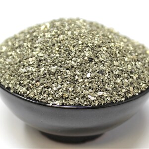 May include: A black bowl filled with a large amount of small, shiny, metallic gold and silver pyrite crystals.