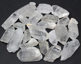 May include: A collection of clear quartz crystals, also known as rock crystal, with various sizes and shapes. The crystals are translucent and have a natural, raw appearance.