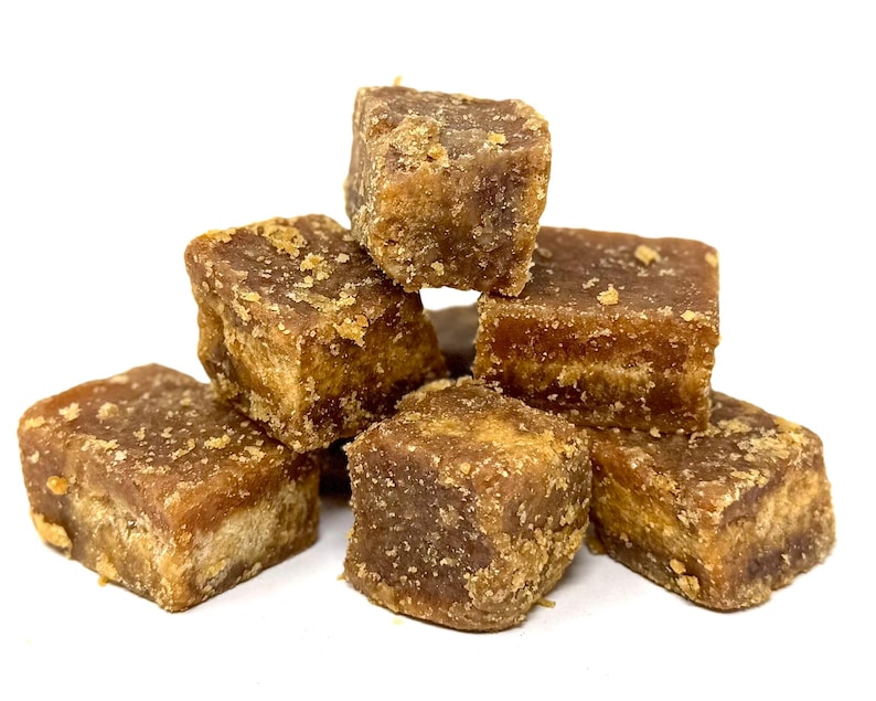 Peut inclure: Plusieurs cubes bruns, probablement du sucre solidifi&eacute; ou une confiserie similaire. Les blocs ont une surface rugueuse et textur&eacute;e. L'arri&egrave;re-plan est blanc.