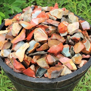 May include: A wooden bowl filled with a variety of red, brown, and white jasper chips. The chips are irregularly shaped and have a natural, polished finish.