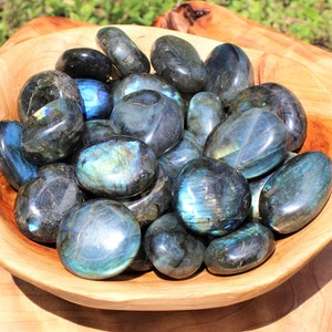 May include: A bowl filled with smooth, polished labradorite stones. The stones are a deep blue with iridescent flashes of green and gold.