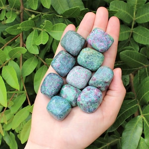 May include: A collection of tumbled green and pink ruby zoisite stones. The stones are smooth and polished, with a variety of shades of green and pink.