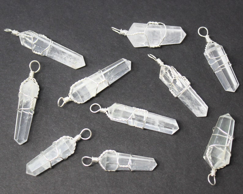 May include: Ten clear quartz crystal pendants wrapped in silver wire. Each pendant has a loop at the top for hanging.
