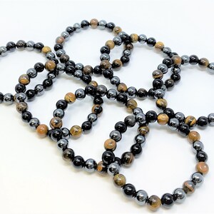 Pode incluir: Seis pulseiras feitas com contas de olho de tigre e hematita. As pulseiras s&atilde;o marrons, douradas, pretas e prateadas.