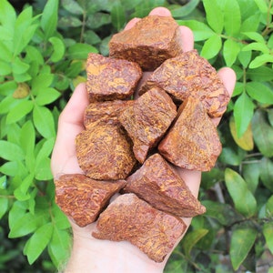 May include: A collection of red and orange jasper stones with a swirling pattern. The stones are rough and have a natural, unpolished finish.