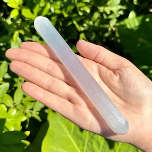 May include: A white selenite wand with a smooth, polished surface. The wand is approximately 6 inches long and has a rounded end.