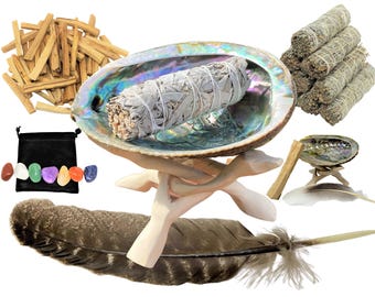 May include: A collection of ritual items including a large iridescent abalone shell on a wooden tripod stand, a white sage smudge stick, a bundle of palo santo wood sticks, a stack of sage bundles, a black pouch, seven polished crystals, and feathers.