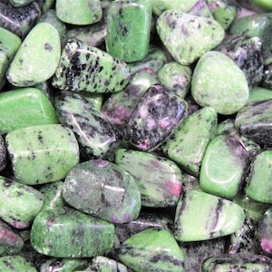 May include: A collection of green, black, and pink tumbled stones. The stones are smooth and polished, with a variety of patterns and textures.