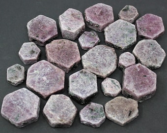 May include: A collection of 18 rough, purple-pink, hexagonal shaped gemstones. The gemstones are various sizes and have a natural, unpolished finish.
