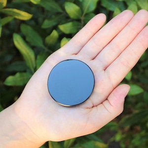 May include: A black round disc with a reflective surface.