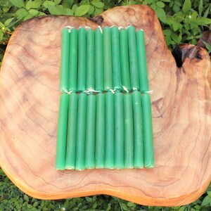 May include: A set of 20 green taper candles arranged in two rows on a wooden surface. The candles are approximately 6 inches long.
