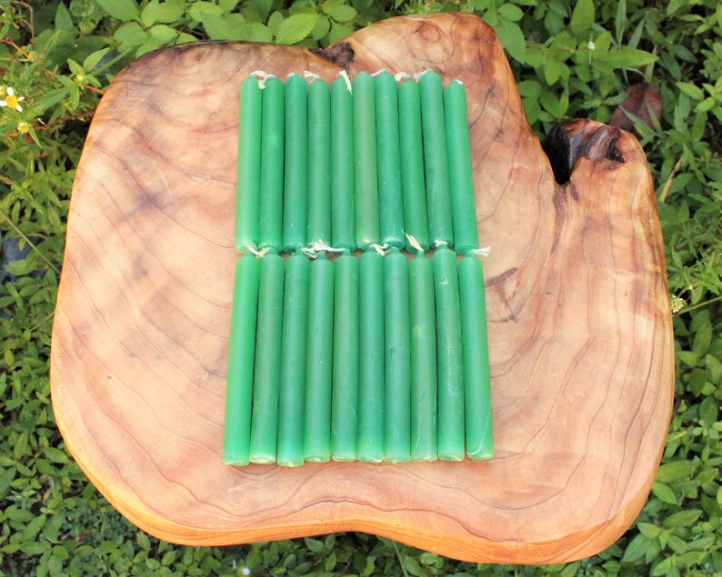 May include: A set of 20 green taper candles arranged in two rows on a wooden surface. The candles are approximately 6 inches long.
