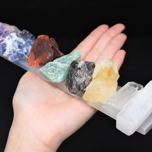 May include: A set of seven chakra crystals, including amethyst, lapis lazuli, carnelian, aventurine, black obsidian, citrine, and selenite, arranged on a selenite charging plate.
