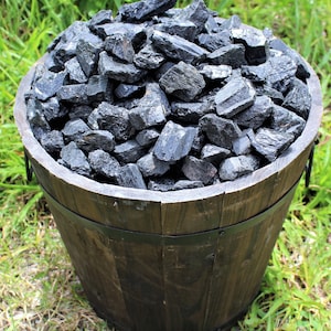 May include: A wooden barrel filled with black tourmaline crystals. The crystals are rough and have a natural, unpolished look.