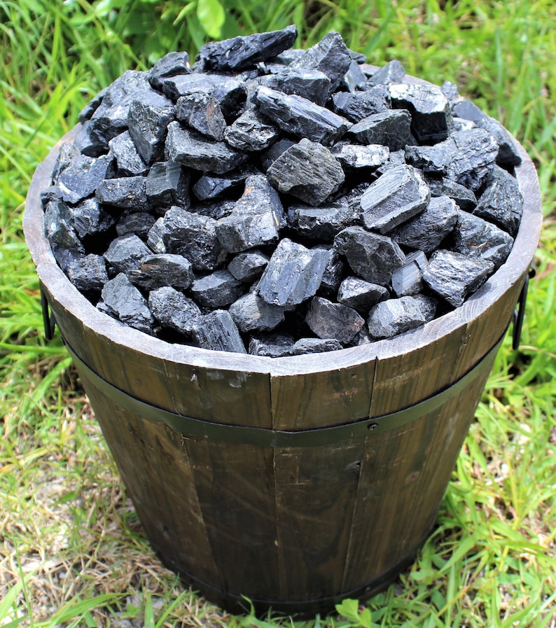 May include: A wooden barrel filled with black tourmaline crystals. The crystals are rough and have a natural, unpolished look.