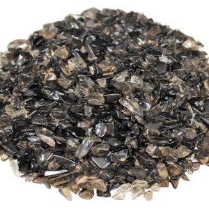 May include: A pile of smoky quartz chips, a variety of quartz that is brown to black in color. The chips are various sizes and shapes, and some have a translucent quality.