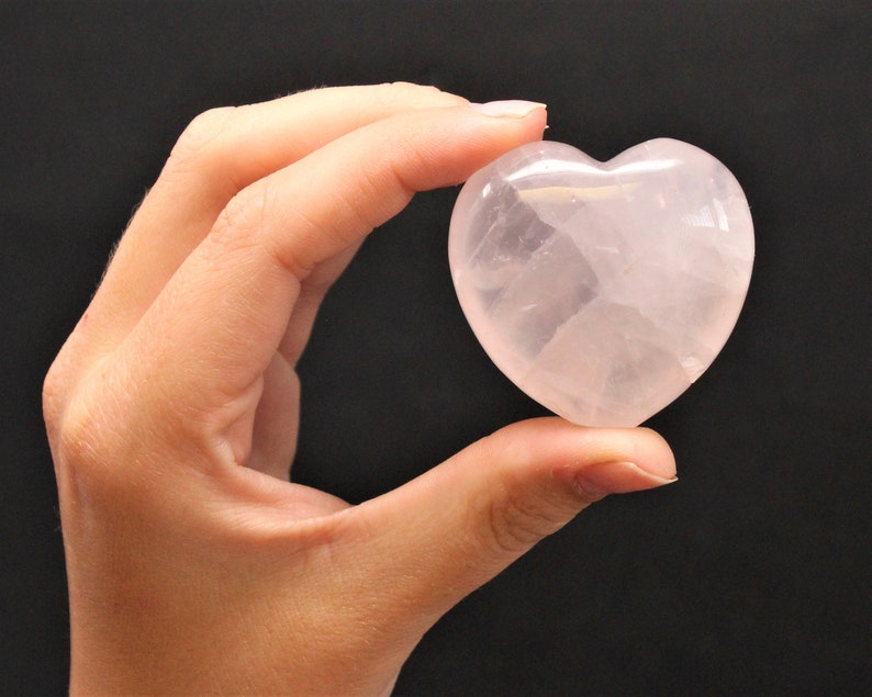 A Large Rose Quartz Heart held between two fingers