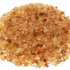 May include: A pile of small, translucent, amber-colored gemstones. The stones are irregularly shaped and have a natural, rough texture.
