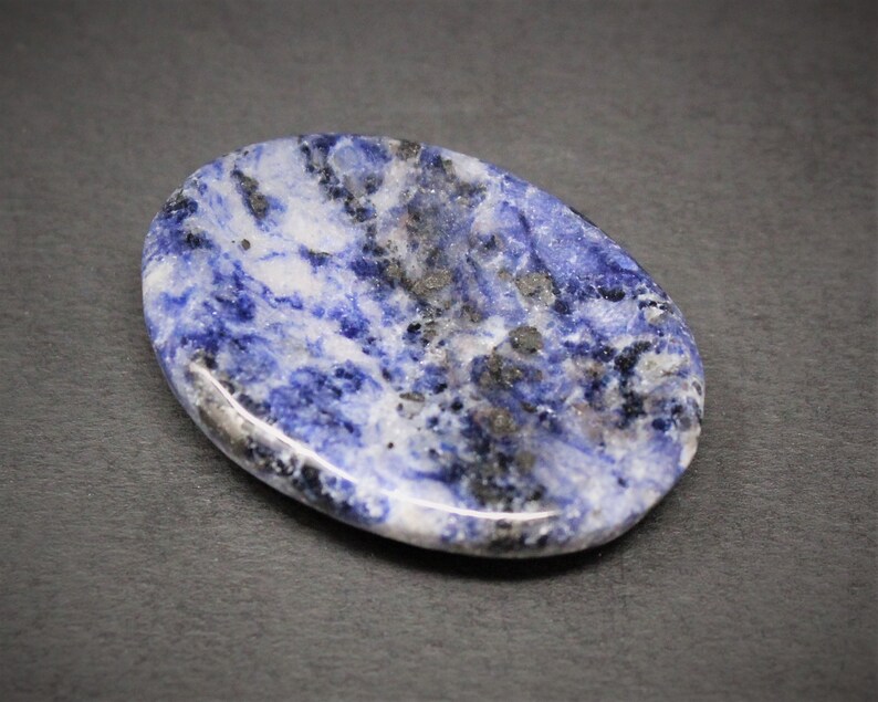 Op de afbeelding: Een ovale, gepolijste steen in blauw en wit met donkergrijze aderen. De steen is glad en heeft een glanzende afwerking.
